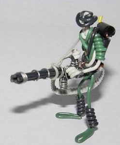 Kleines aus Drähten geformtes Männchen mit einer ebenfalls aus Drähten geformten Gatling-Kanone